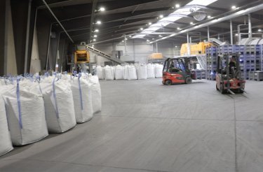 Waste-filled big bags on the floor near a red truck